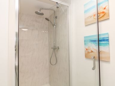 A shower area with a glass door and two seashell-themed pictures on the wall at The View in Cardinham