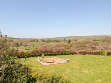 A garden with benches on a wooden platform overlooking fields and trees at The View in Cardinham