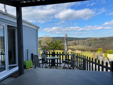 A patio with two chairs and a small round table overlooking a garden and countryside at The View in Cardinham