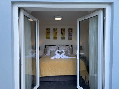 A bedroom with a bed covered in a yellow bedspread and towel swans on the bed at The View in Cardinham