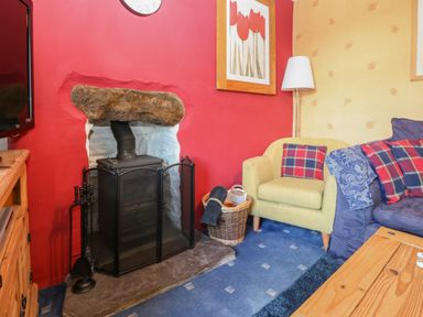 A living room with a wood stove fireplace armchair sofa and coffee table at Bod Feurig in Penygroes