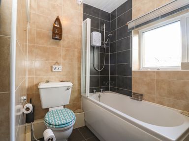 A bathroom with a toilet and bathtub with shower at Bod Feurig in Penygroes