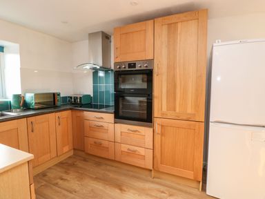 A kitchen with wooden cabinets a double oven a white refrigerator and green appliances at Stable Cottage in Hallbankgate