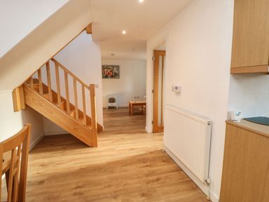A hallway with wooden stairs and a radiator next to a wooden table at Stable Cottage in Hallbankgate