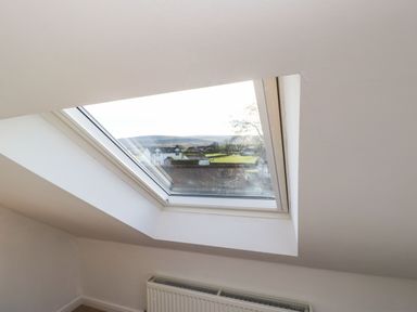 A skylight window showing an outside view with a radiator below at Stable Cottage in Hallbankgate
