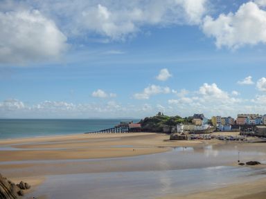 A coastal town with a sandy beach a pier and colorful buildings at The Nest Brython in Tenby