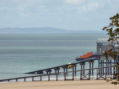 A lifeboat station with ramps and boats by a sandy beach and sea at The Nest Brython in Tenby