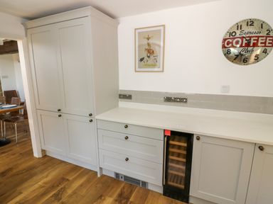 A kitchen area with light gray cabinets a countertop and a wine cooler at The Paddock in New Yatt near Witney