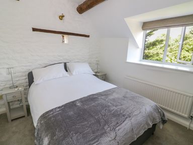 A bedroom with a double bed two bedside tables with lamps a window and a radiator at The Paddock in New Yatt near Witney