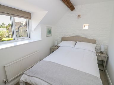 A bedroom with a double bed between two bedside tables under a window at The Paddock in New Yatt near Witney