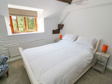 A bedroom with a white bed and two bedside tables with orange lamps at The Paddock in New Yatt near Witney