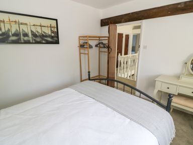 A bedroom with a bed a wooden clothes rack and a dressing table at The Paddock in New Yatt near Witney