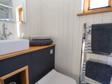A bathroom with a sink and faucet a wooden countertop towels on a cabinet and a towel rack at Cariad Bach in Gwaenysgor near Prestatyn