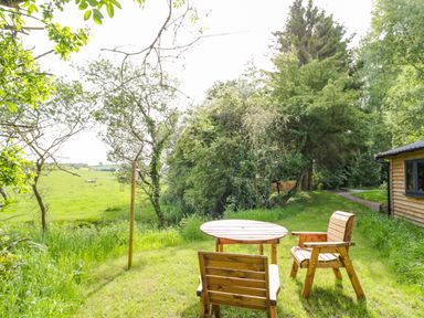 A garden area with two wooden chairs and a round wooden table near a wooden building at Willow in Dunchurch