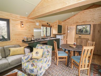 An open living area with a kitchen, dining table with chairs, sofa, and armchair at Dragonfly in Dunchurch