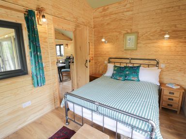 A bedroom with a metal bed frame striped bedding and butterfly cushions at Dragonfly in Dunchurch