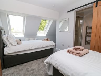 A bedroom with two single beds towels and a wall mirror at Willow Cottage in Combe Martin