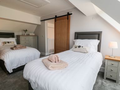 A bedroom with two single beds and a wooden sliding door at Willow Cottage in Combe Martin