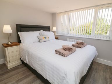 A bedroom with a bed with white linens towels on bed and bedside tables with lamps at Willow Cottage in Combe Martin