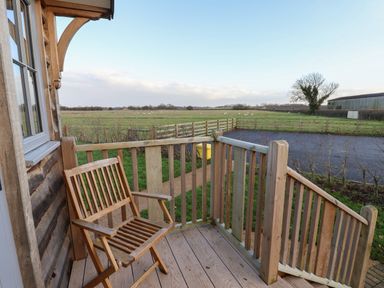 A wooden chair on a small wooden balcony overlooking a field with grazing sheep at Arts and Crafts in Bolton Percy near Tadcaster