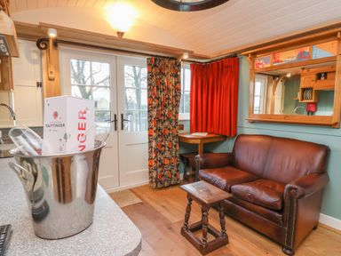 A living room with a brown leather sofa a small wooden table and a champagne bucket on a countertop at Arts and Crafts in Bolton Percy near Tadcaster