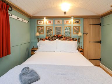 A bedroom with a double bed white linens patterned headboard wall art bedside lamps and wooden door at Arts and Crafts Bolton Percy near Tadcaster