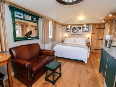 A bedroom with a leather sofa a bed and a green framed mirror at Amy Johnson in Bolton Percy near Tadcaster