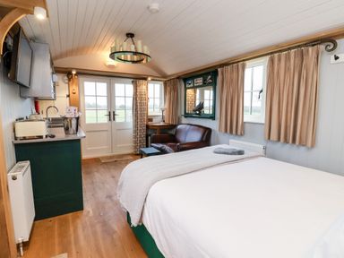 A bedroom with a bed sofa kitchenette and double doors at Amy Johnson Bolton Percy near Tadcaster