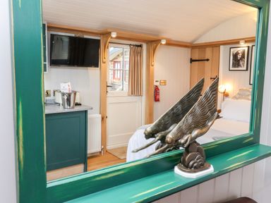 A bedroom with a mounted television a bed a green cabinet and a decorative sculpture at Amy Johnson in Bolton Percy near Tadcaster