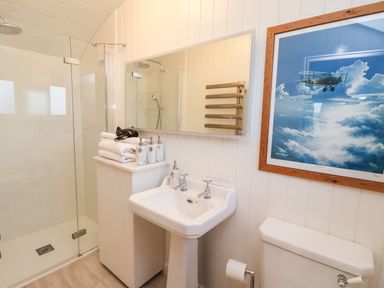 A bathroom with a shower, sink, toilet, towels, and a framed airplane picture on the wall at Amy Johnson in Bolton Percy near Tadcaster