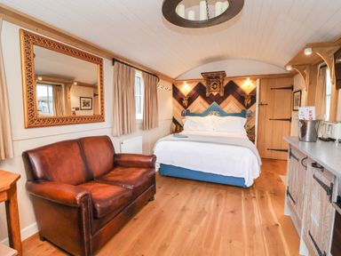 A bedroom with a brown leather sofa a bed wooden floor and a kitchen counter at The White Princess in Bolton Percy near Tadcaster