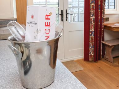 A kitchen counter with a metal ice bucket holding a champagne box and glasses near a door with patterned curtains at The White Princess in Bolton Percy near Tadcaster