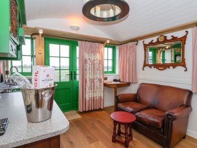 A room with a brown leather sofa a red wooden stool green doors and windows and a table with a metal ice bucket at Folklore in Bolton Percy near Tadcaster