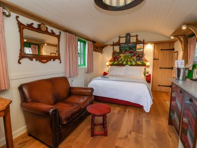 A bedroom with a leather sofa a bed with a colorful headboard and a wooden door at Folklore Bolton Percy near Tadcaster