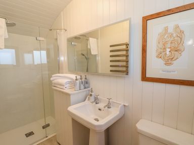 A bathroom with a shower enclosure towels a pedestal sink a mirror a towel rack and wall art at Folklore Bolton Percy near Tadcaster