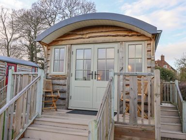 A wooden cabin with a curved roof and double doors with windows at Folklore in Bolton Percy near Tadcaster