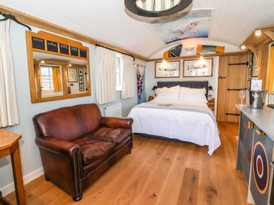 A bedroom with a leather sofa, a bed, and framed airplane pictures at The Fenton in Bolton Percy near Tadcaster