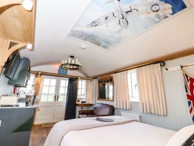 A bedroom with a bed a leather sofa a mirror and a kitchen area at The Fenton in Bolton Percy near Tadcaster