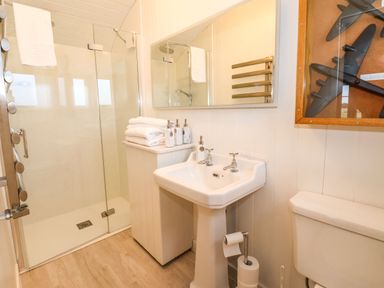 A bathroom with a shower, sink, toilet, towels, and framed airplane models at The Fenton in Bolton Percy near Tadcaster
