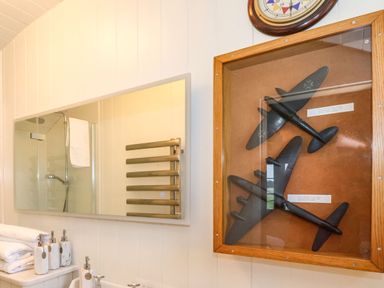 A bathroom with a mirror reflecting a shower and towel rack and a display case with model airplanes at The Fenton in Bolton Percy near Tadcaster