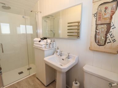 A bathroom with a glass shower, pedestal sink with soap dispensers, white towels, and a toilet at The Egyptologist in Bolton Percy near Tadcaster