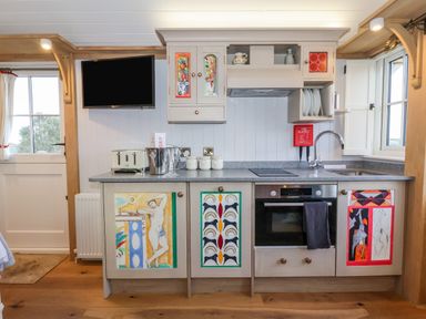 A kitchen with a stove oven sink and cabinets with colorful artwork at The Studio in Bolton Percy near Tadcaster