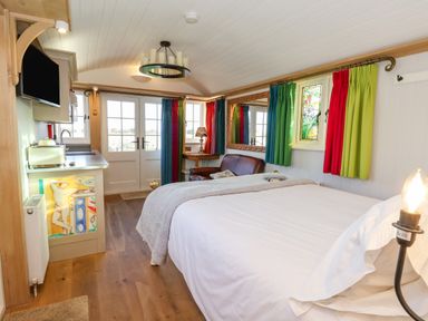 A bedroom with a bed a sofa a small kitchenette and colorful curtains at The Studio in Bolton Percy near Tadcaster