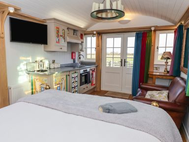 A small kitchen and living area with a bed a leather sofa and double doors leading outside at The Studio in Bolton Percy near Tadcaster