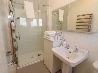 A bathroom with a shower enclosure a sink with faucets and towels at The Studio in Bolton Percy near Tadcaster