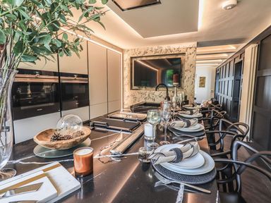 A kitchen with a long black countertop set for dining with plates glasses and napkins at Whisk Away Cottage in Greystoke near Troutbeck Near Penrith
