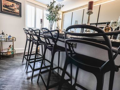 A kitchen with black bar stools around a counter with bottles on a bar cart at Whisk Away Cottage in Greystoke near Troutbeck Near Penrith