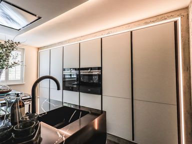 A kitchen with a black sink, a faucet, built-in ovens, cabinets, a window with shutters and a vase with plants at Whisk Away Cottage in Greystoke near Troutbeck Near Penrith