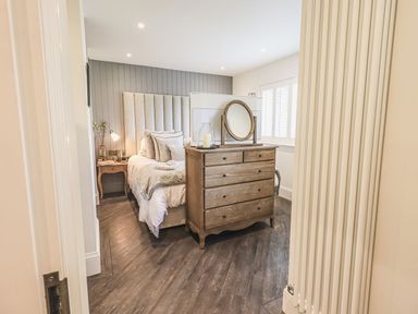 A bedroom with a bed bedside table and wooden dresser with mirror at Whisk Away Cottage Greystoke near Troutbeck Near Penrith