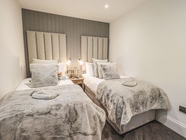 A bedroom with two single beds and bedside table between them at Whisk Away Cottage Greystoke near Troutbeck Near Penrith